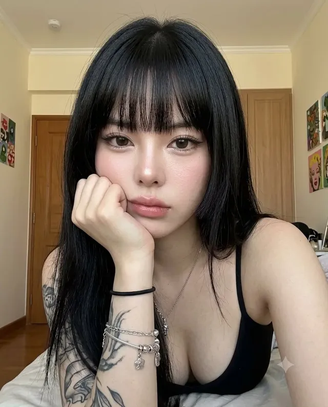 Medium close-up smartphone portrait of a woman with a Hime cut hairstyle, resting her cheek on her fist. She has a thoughtful, slightly melancholic expression, detailed makeup, and is in a casual bedroom setting with a Dutch tilt.