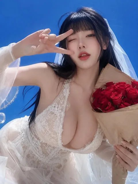 Bride holding red roses, making a peace sign, with a soft focus effect.