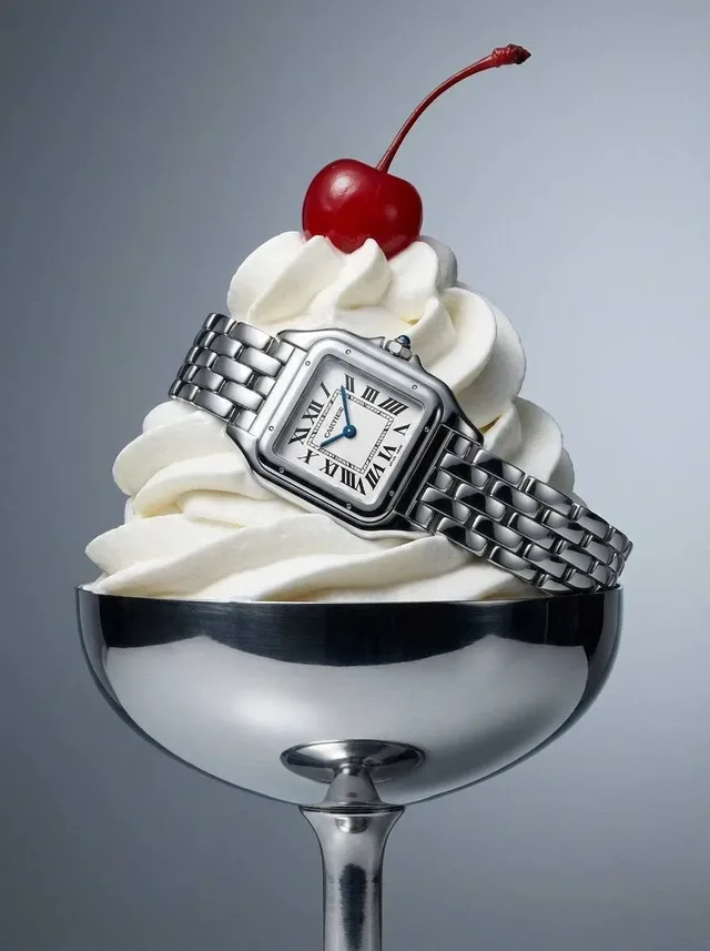 Fine jewelry artfully arranged on a swirl of white whipped cream in a silver ice cream sundae dish, with a fresh strawberry on top, lit by soft studio light.
