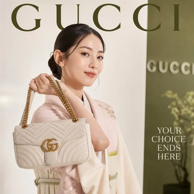 Elegant Japanese woman in a pink and white dress holding a Gucci handbag, smiling confidently, on a magazine cover.