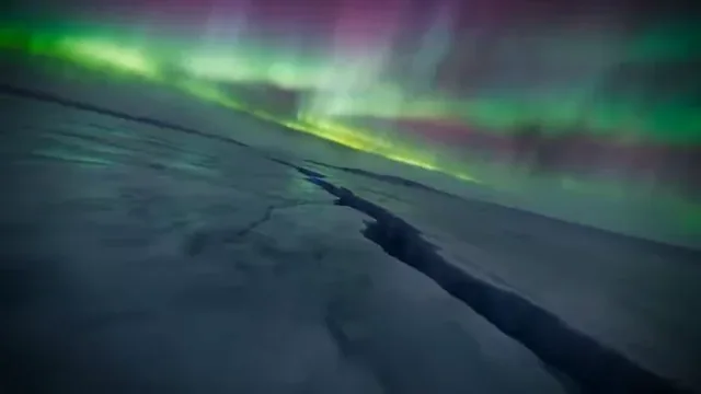 First-person view of a drone diving through a frozen arctic canyon with aurora lights, shattering a waterfall to reveal a bioluminescent alien ocean.