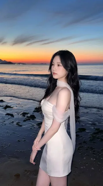 Ultra-realistic portrait of a young East Asian woman in a white satin mini dress on a beach at blue hour, with a flowing scarf and a sunset sky.