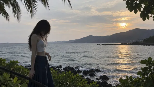 An amateur smartphone snapshot of a young woman standing by a tropical coastal walkway with the sea in the background.