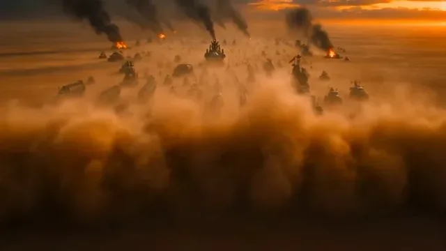 A warlord in black steel armor and a long coat stands on a war machine, removing his helmet as explosions and motorcycles surround him in a dusty desert sunset.