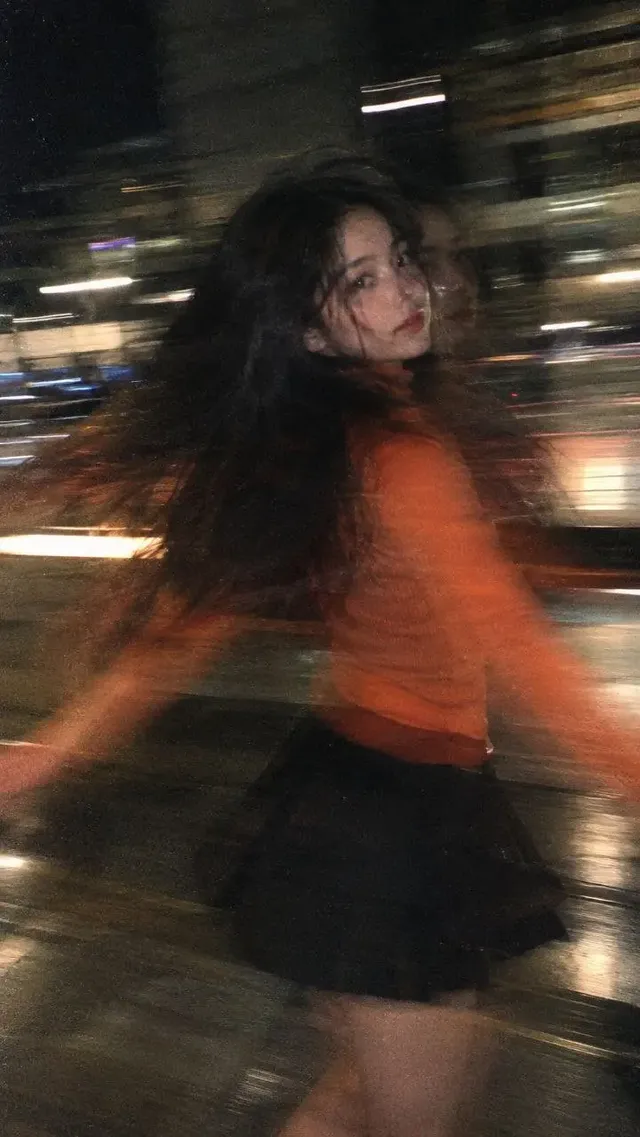 Vertical fashion portrait of an East Asian girl spinning with extreme motion blur and heavy film grain.