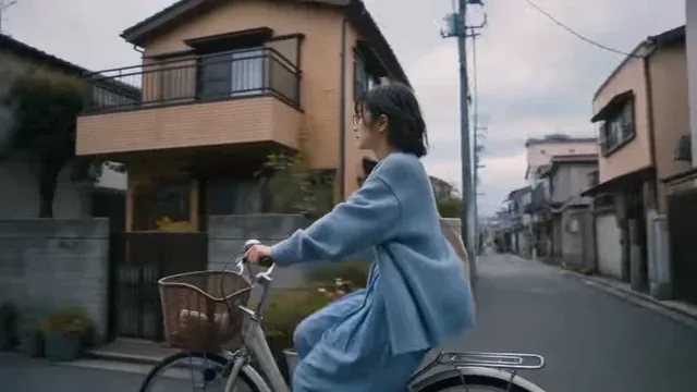 Young Japanese woman in a cream cardigan and denim, riding a bicycle and walking through a quiet, traditional Japanese neighborhood with canals and shrines.