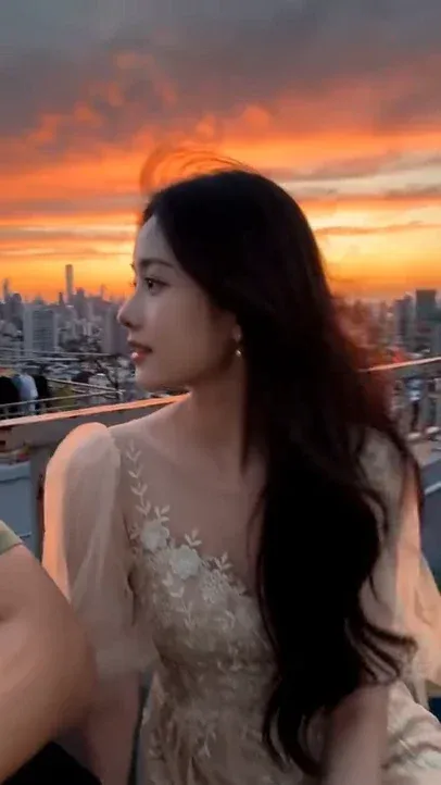 First-person POV video of a sweet girlfriend with long black hair leaning on her boyfriend's shoulder during a windy sunset on a city rooftop.