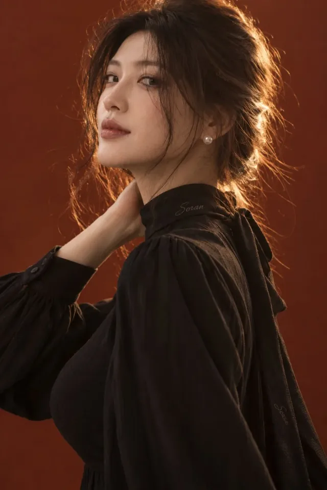 Close-up portrait of an East Asian woman looking back at the camera, with warm golden backlighting creating a halo effect around her loose hair and shoulder.