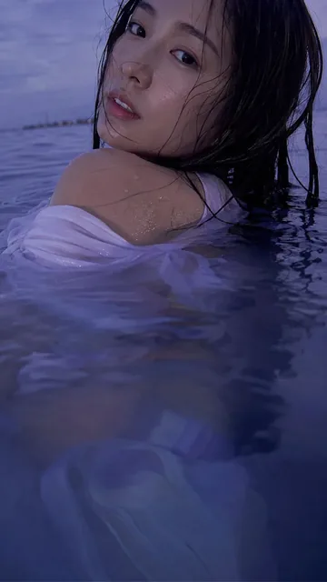 A photorealistic close-up of a Japanese woman's face partially submerged in deep violet-blue water, looking softly over her shoulder at the camera.